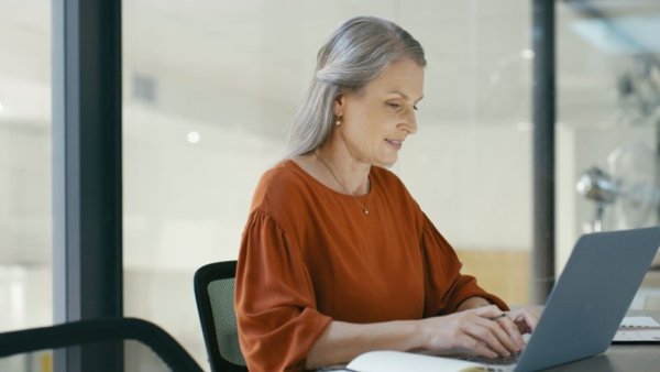 Image of a person working at a laptop touching a bar chart visualization. 